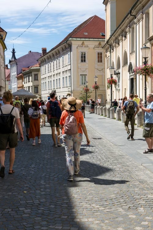Turyści spacerują po brukowanej ulicy wśród historycznych kamienic